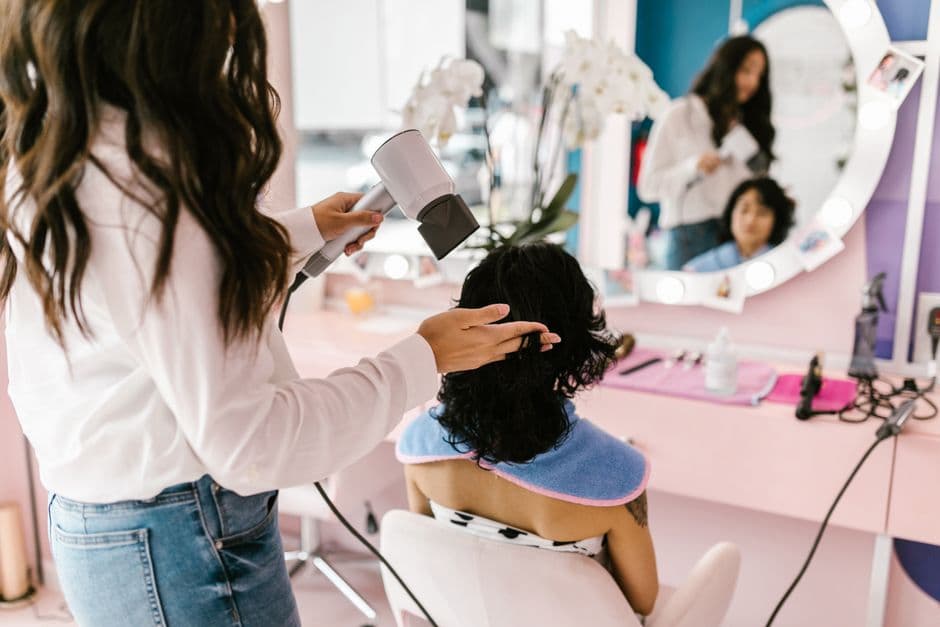 Stylist blow-drying a client in a salon